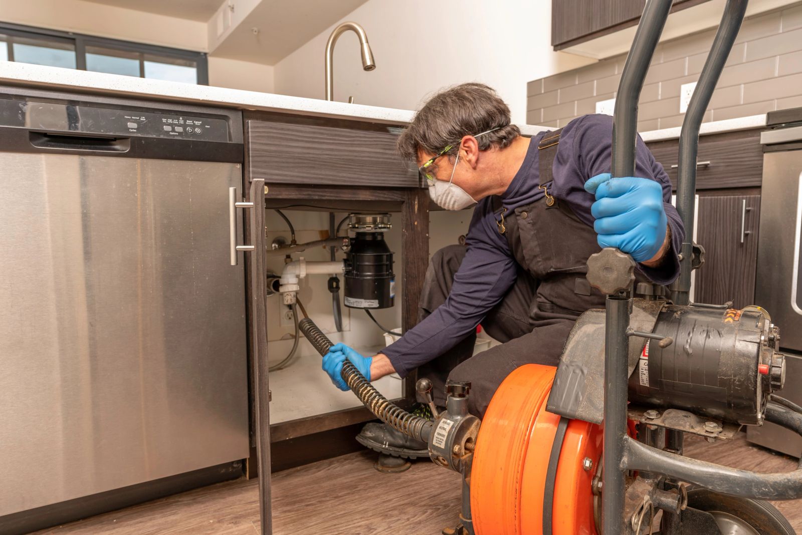 Plumber clearing a drain with an auger
